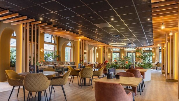 A modern interior with wooden flooring, round tables, and cushioned chairs.