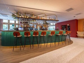 A bar area with a curved counter, multiple stools, and a variety of bottles and glasses.