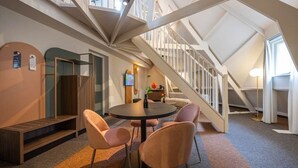 Un intérieur moderne avec un escalier, une table ronde entourée de chaises et un banc.