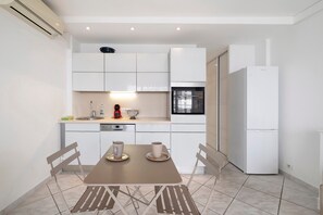 Una cucina moderna con mobili bianchi, forno integrato e frigorifero.