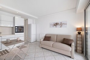 Een modern appartement met een kitchenette, een bank, een eettafel en een lamp.
