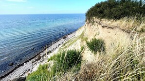A coastal landscape with a clear view of the sea, a sandy beach, and a grassy cliff. - Vacation at the Baltic Sea, freshly renovated, quiet vacation apartment, 3.5 km to the beach (OT Niederklütz)