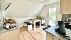 A modern kitchen with a dining area, a coffee machine, and a view of the outdoors. - Vacation at the Baltic Sea, freshly renovated, quiet vacation apartment, 3.5 km to the beach (OT Niederklütz)