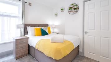 A bedroom with a bed, bedside tables, a window, and wall decorations.