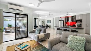 A modern living room with a grey sofa, a coffee table, and a dining area with chairs.