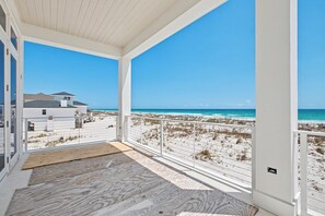 Ein überdachter Balkon mit Blick auf Strand und Meer.