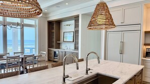 A modern kitchen with a large island, stainless steel sink, and pendant lighting. - New Luxury Gulf Front Home | Event Friendly | Elevator | Sleeps 24 (Pensacola Beach)