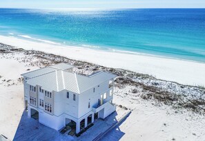 Ein zweistöckiges Strandhaus mit flachem Dach, großen Fenstern und einem Balkon.