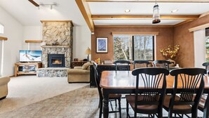 A spacious living area with a stone fireplace, wooden ceiling beams, a dining table with chairs, and a television. - Frisco Mountain Home | Clubhouse, Pool & Hot Tubs Nearby (Frisco)