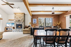 A spacious living area with a stone fireplace, wooden ceiling beams, a dining table with chairs, and a television. - Frisco Mountain Home | Clubhouse, Pool & Hot Tubs Nearby (Frisco)