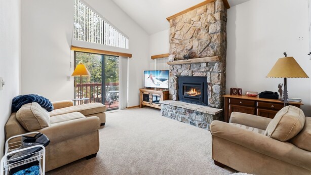 A spacious living room with a stone fireplace, two sofas, a TV, and a balcony with large windows. - Frisco Mountain Home | Clubhouse, Pool & Hot Tubs Nearby (Frisco)