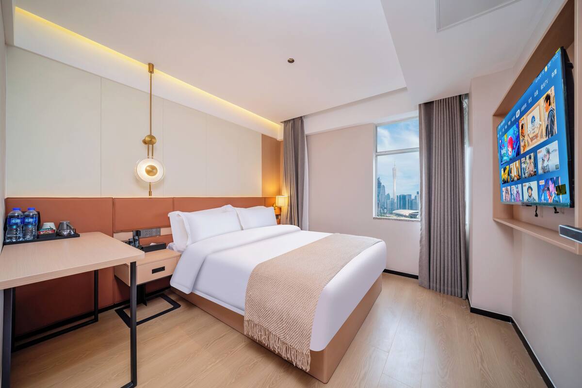 A hotel room with a bed, desk, and TV.