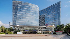 A modern building with a glass facade, a pedestrian bridge, and a sign with Chinese characters. - Ritz Star City View Residence  (Guangzhou)