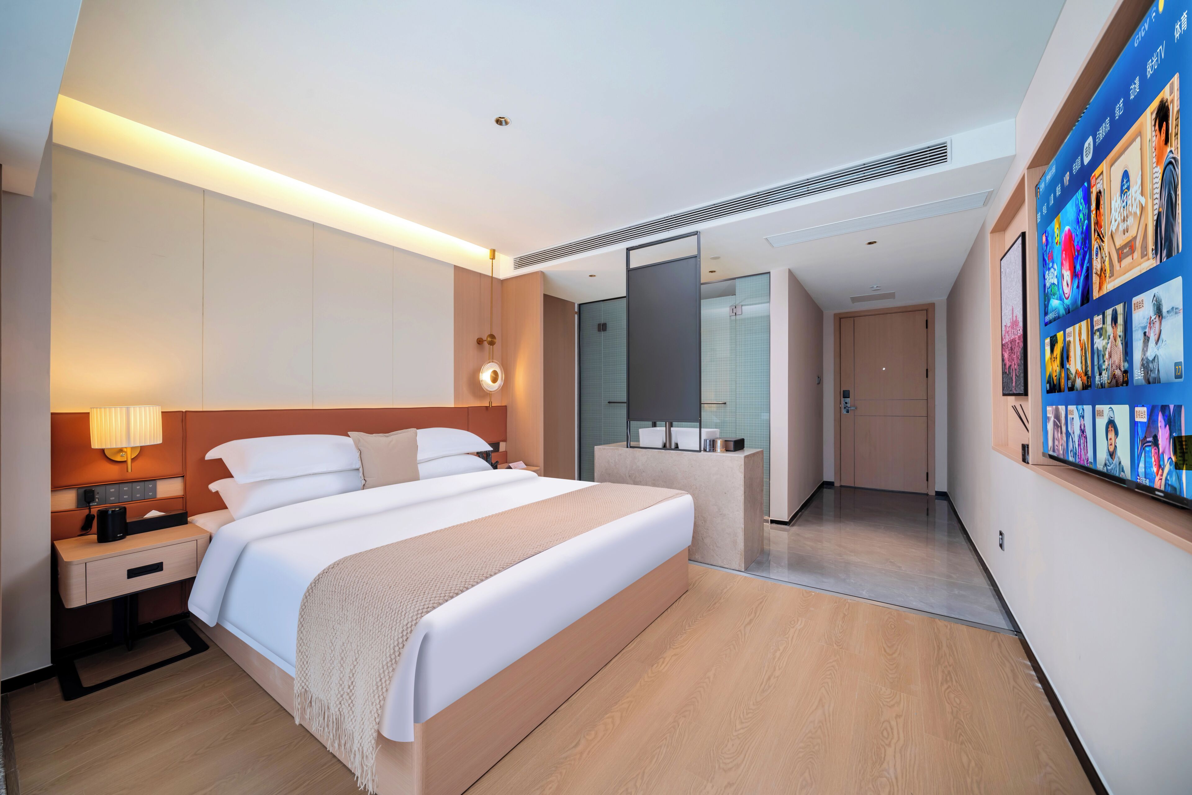 Une chambre d’hôtel moderne avec un grand lit, une table de chevet, une lampe et un mur orné de tableaux.