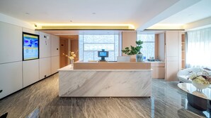 A modern hotel lobby with a marble reception desk, a digital information screen, and a large window providing natural light. - Ritz Star City View Residence  (Guangzhou)
