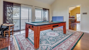 Une table de billard dans une pièce spacieuse, dotée d’une grande fenêtre, d’un coin repas et offrant une vue sur l’extérieur.