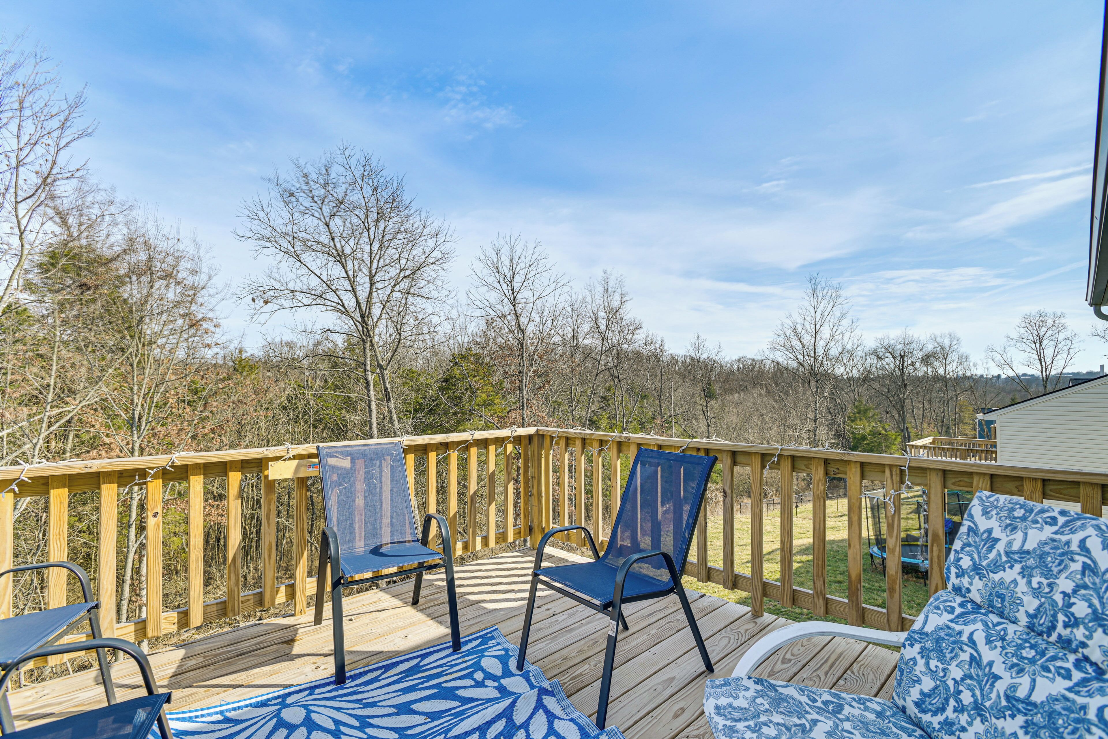 Une terrasse en bois, dotée de chaises et d’un canapé, qui offre une vue sur une zone boisée.