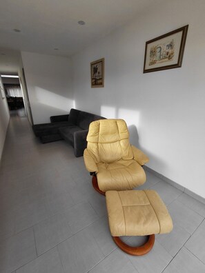 A modern living room with a sofa, a yellow chair, and two framed pictures on the wall. - Town house in a simple commune. (WATTEN)