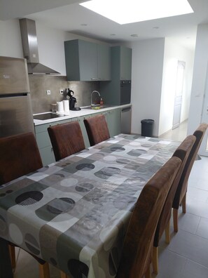 A modern kitchen with a skylight, stainless steel appliances, and a dining area with a patterned tablecloth. - Town house in a simple commune. (WATTEN)