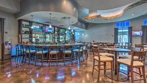 A bar area with a curved ceiling, multiple TVs, and a variety of seating options including bar stools and tables. - Walk to Beach - Palms of Destin Resort Unit (Destin)