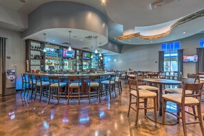 A bar area with a curved ceiling, multiple TVs, and a variety of seating arrangements. - Walk to Beach - Palms of Destin Resort Unit (Destin)