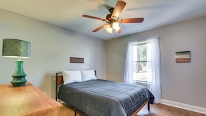 A bedroom with a bed, a ceiling fan, a nightstand, a window with curtains, and a wall-mounted picture. - Families w/ Pets! Emerald Coast Home 9 Mi to Beach (Fort Walton Beach)