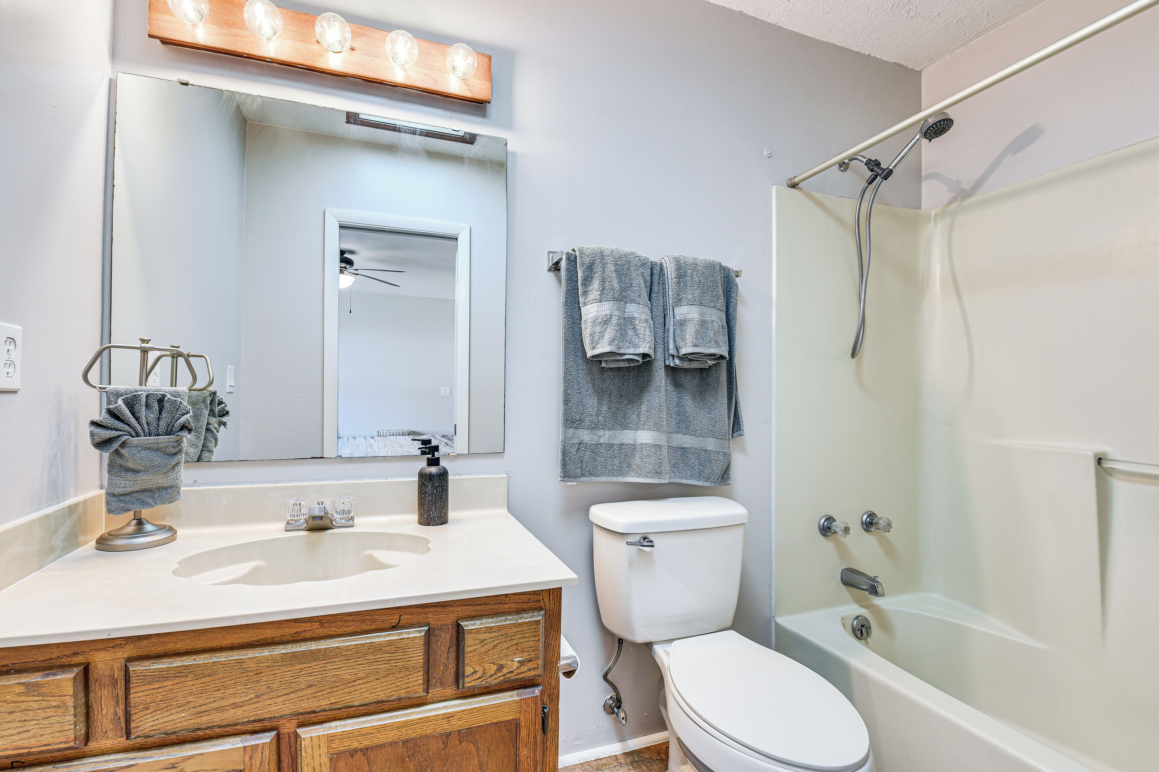 Une salle de bain avec un lavabo blanc, un meuble-lavabo en bois, des toilettes blanches et une douche à parois de verre.