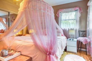 A bedroom with a canopy bed, a bedside table, a chair, and a window with curtains. - Hot Tub, Home Gym, Decks! Retreat 9 Mi to Mt Airy (Ararat)