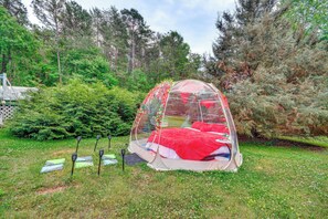 A transparent dome tent with a red interior, surrounded by greenery and trees. - Hot Tub, Home Gym, Decks! Retreat 9 Mi to Mt Airy (Ararat)