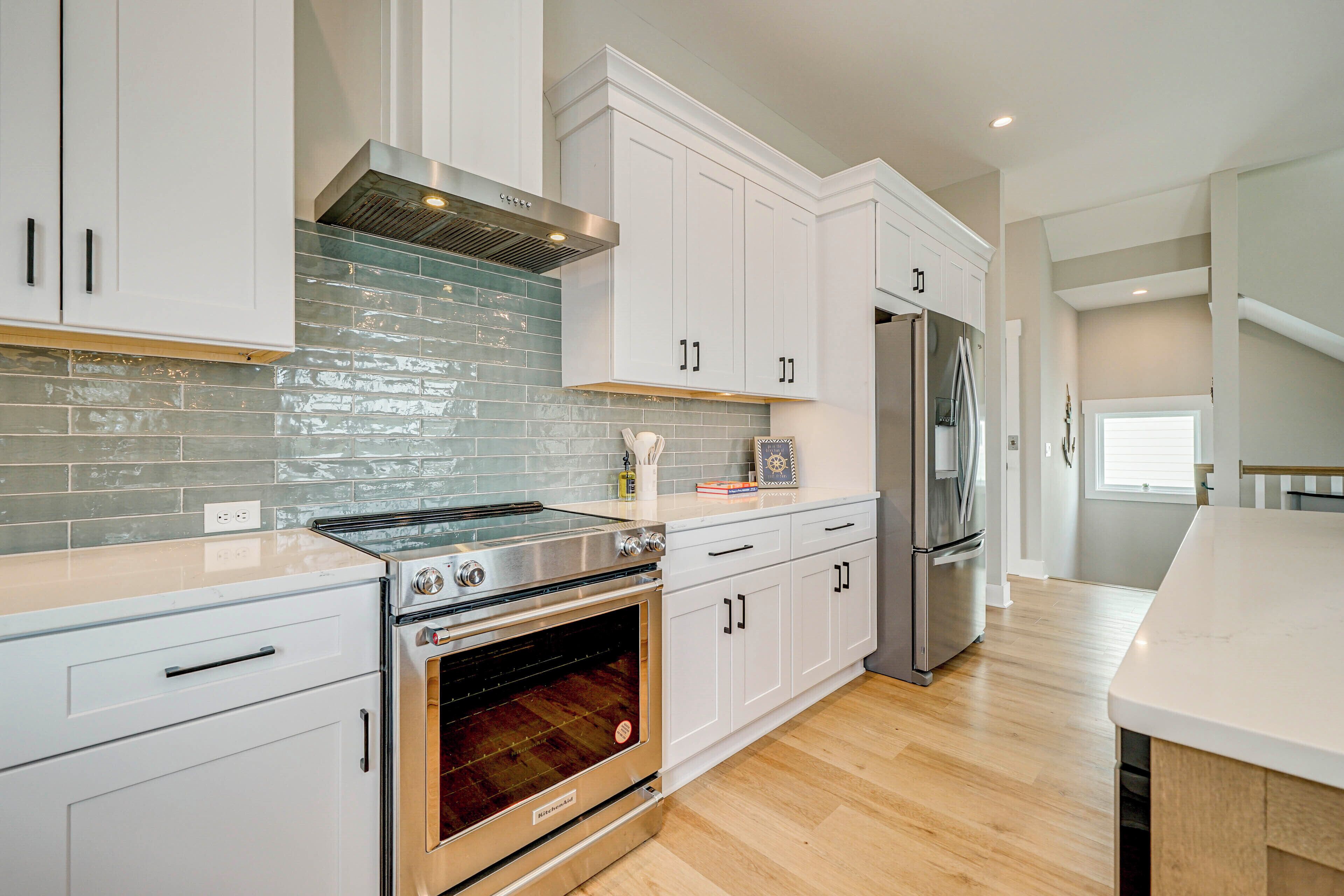A modern kitchen with white cabinets, a stainless steel range, and an oven.