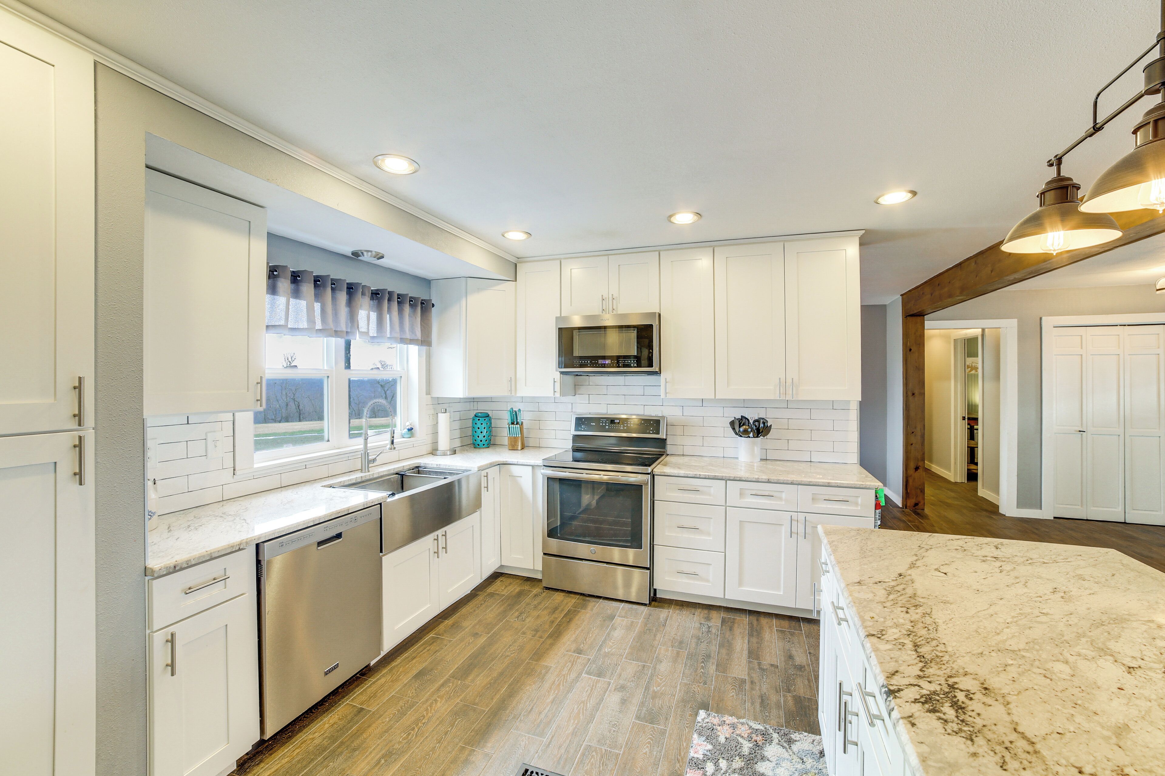 Una cocina moderna con armarios blancos, electrodomésticos de acero inoxidable y piso de madera.