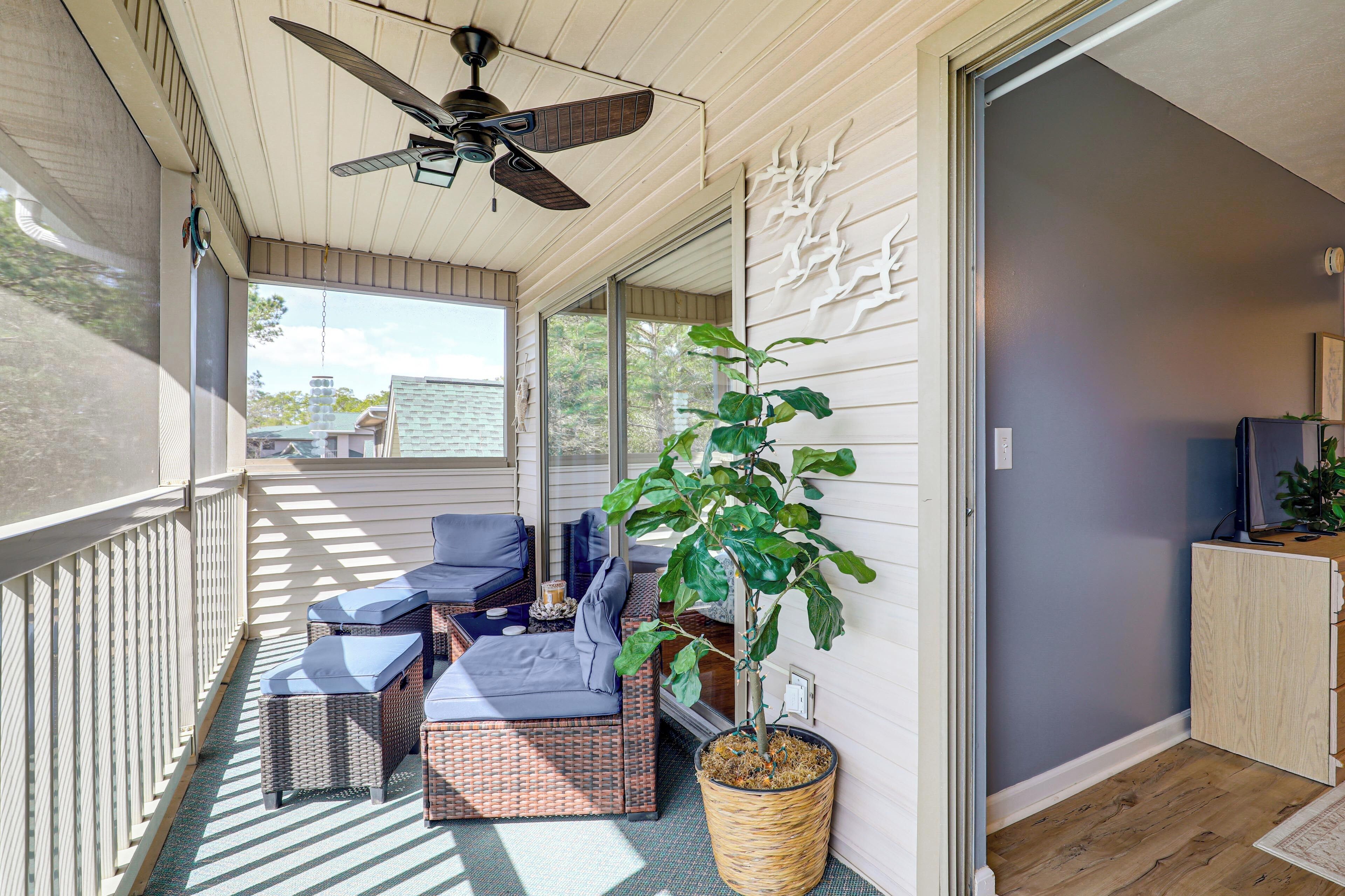 A covered balcony with wicker furniture, a ceiling fan, and a potted plant.