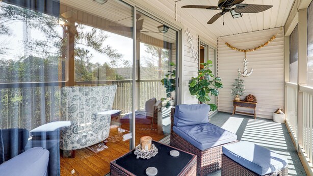 Eine überdachte Veranda mit Korbmöbeln, einem Deckenventilator und Blick ins Freie.