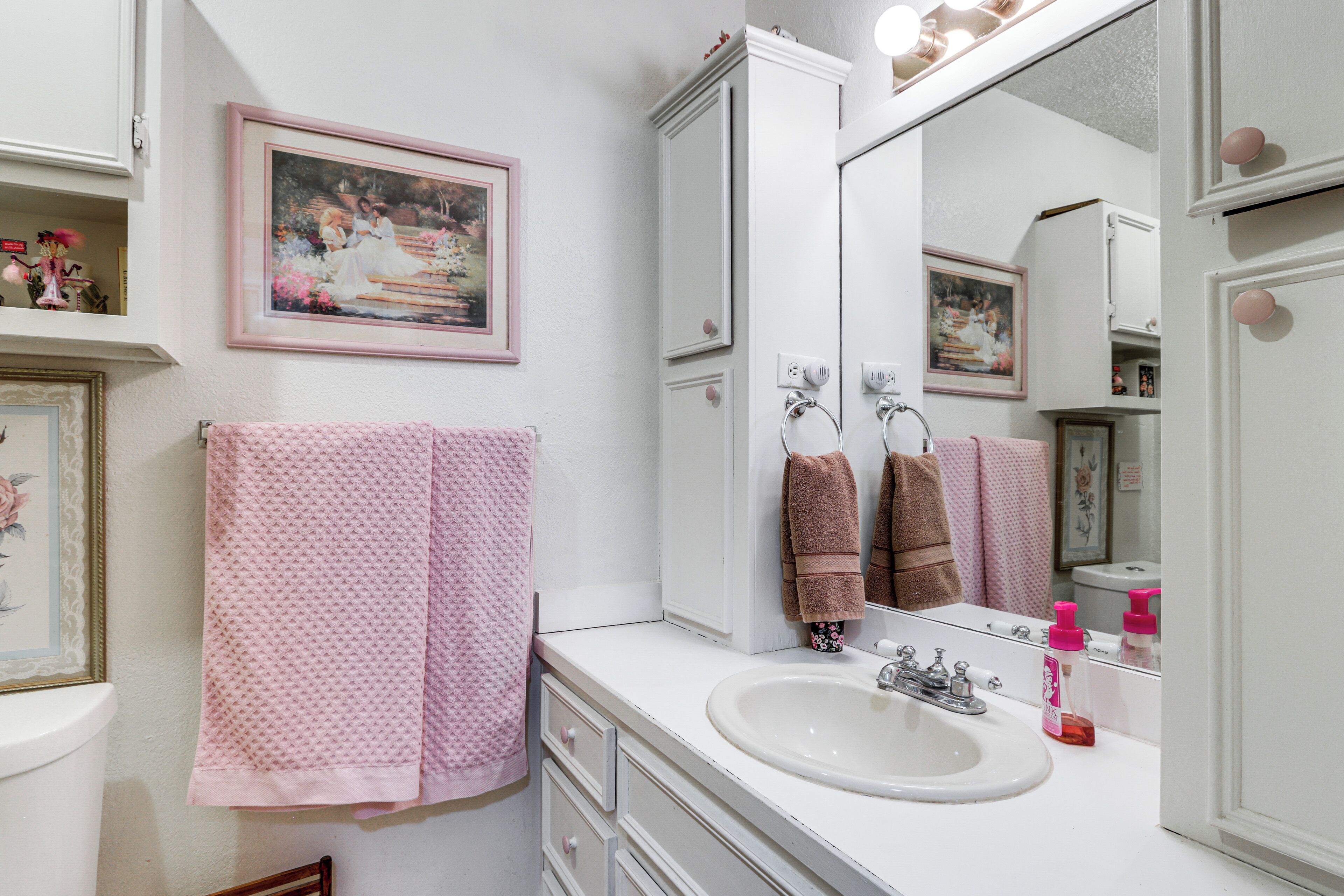 A bathroom with a sink, mirror, and towels.