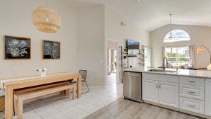 Una cucina moderna con una panca in legno, mobili bianchi e un'ampia finestra.