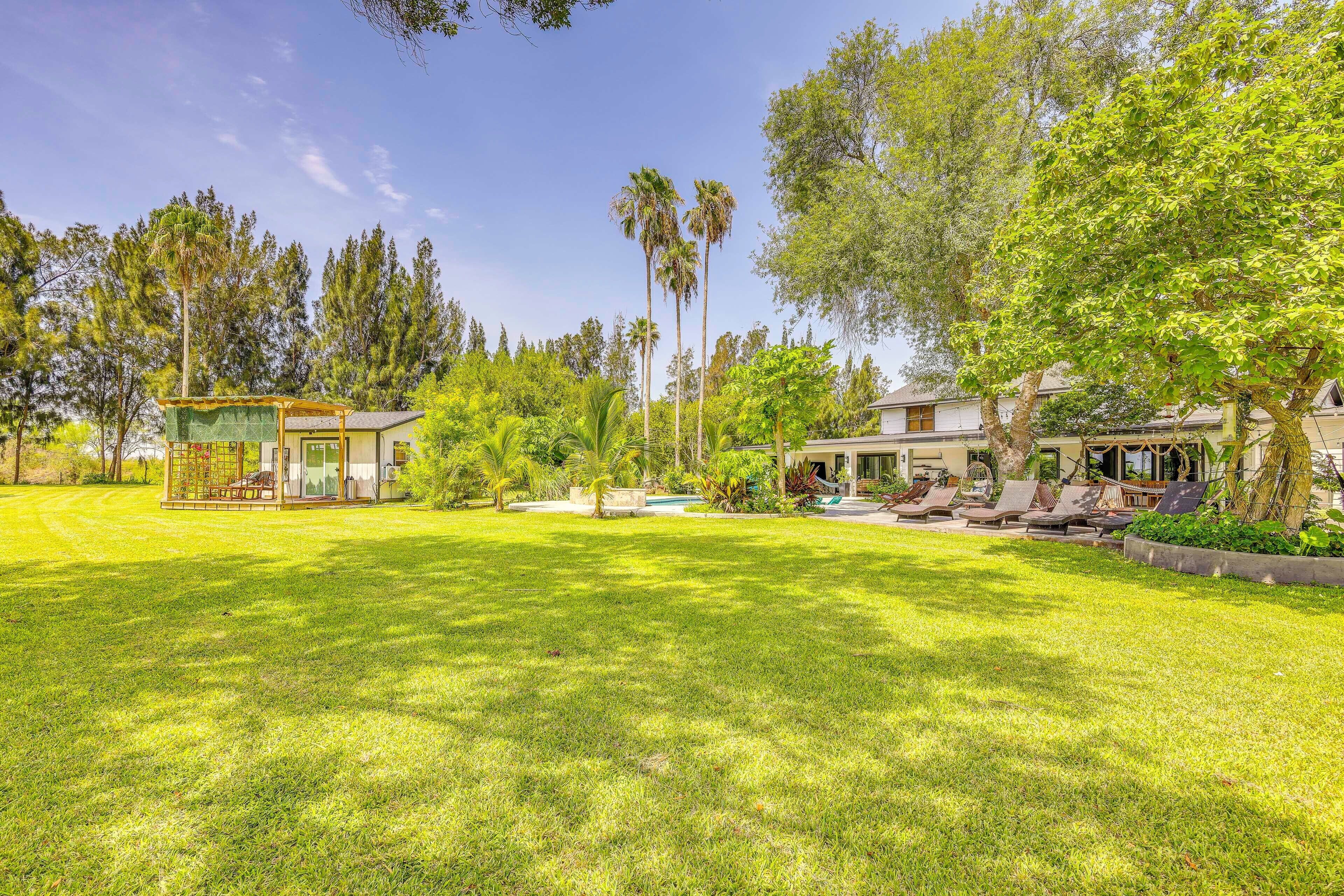 A well-maintained lawn with a pool area, outdoor seating, and a variety of trees and plants.