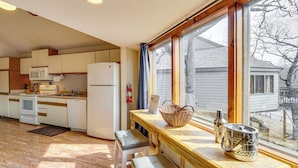 A kitchen with wooden cabinets, a microwave, a refrigerator, and a window with a view of a house. - Pet-friendly Lakefront Escape in Osage Beach (Osage Beach)