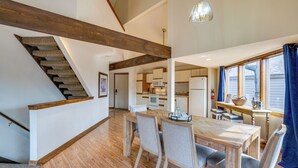 Una cocina amplia con electrodomésticos modernos, un comedor con mobiliario de madera y una escalera con vigas a la vista.
