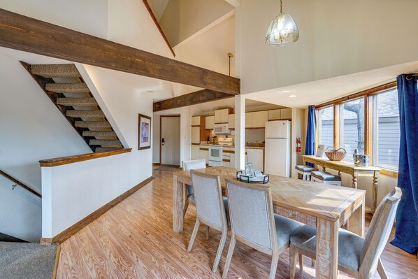 A spacious kitchen with modern appliances, a dining area with wooden furniture, and a staircase with exposed beams. - Pet-friendly Lakefront Escape in Osage Beach (Osage Beach)