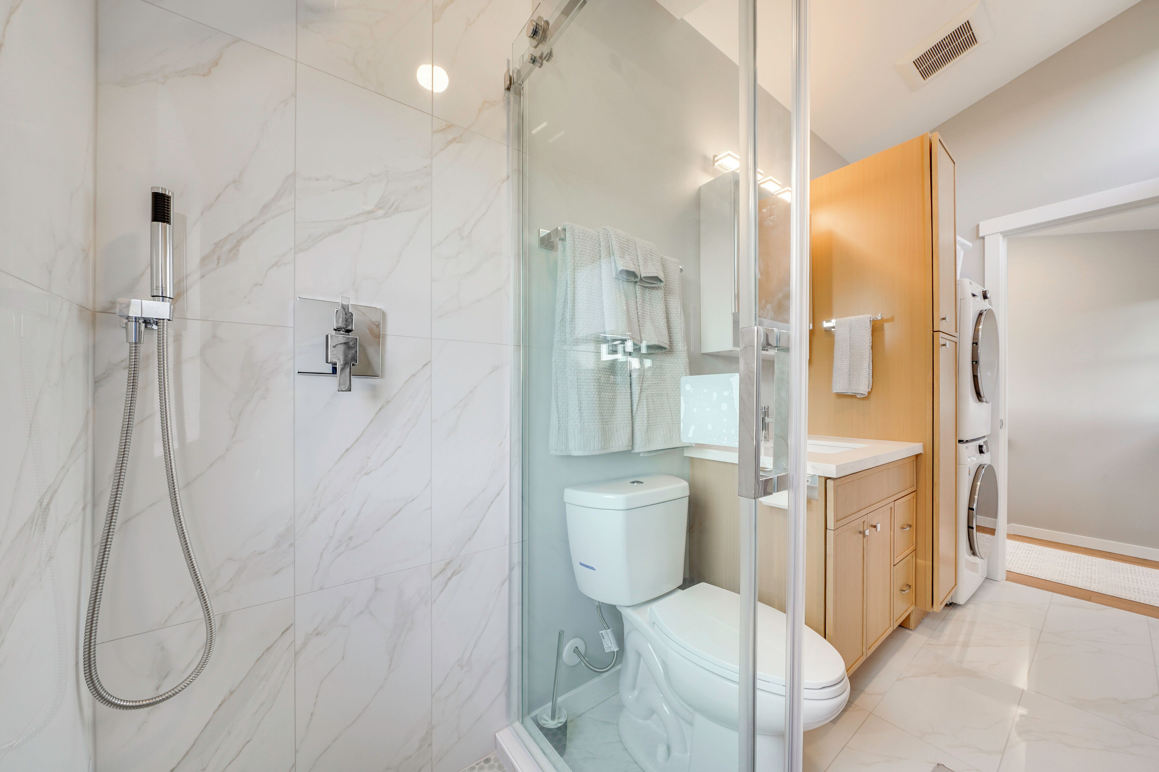 Ein modernes Badezimmer mit einer Duschkabine, einer Toilette und einem Waschbecken mit Spiegel darüber.