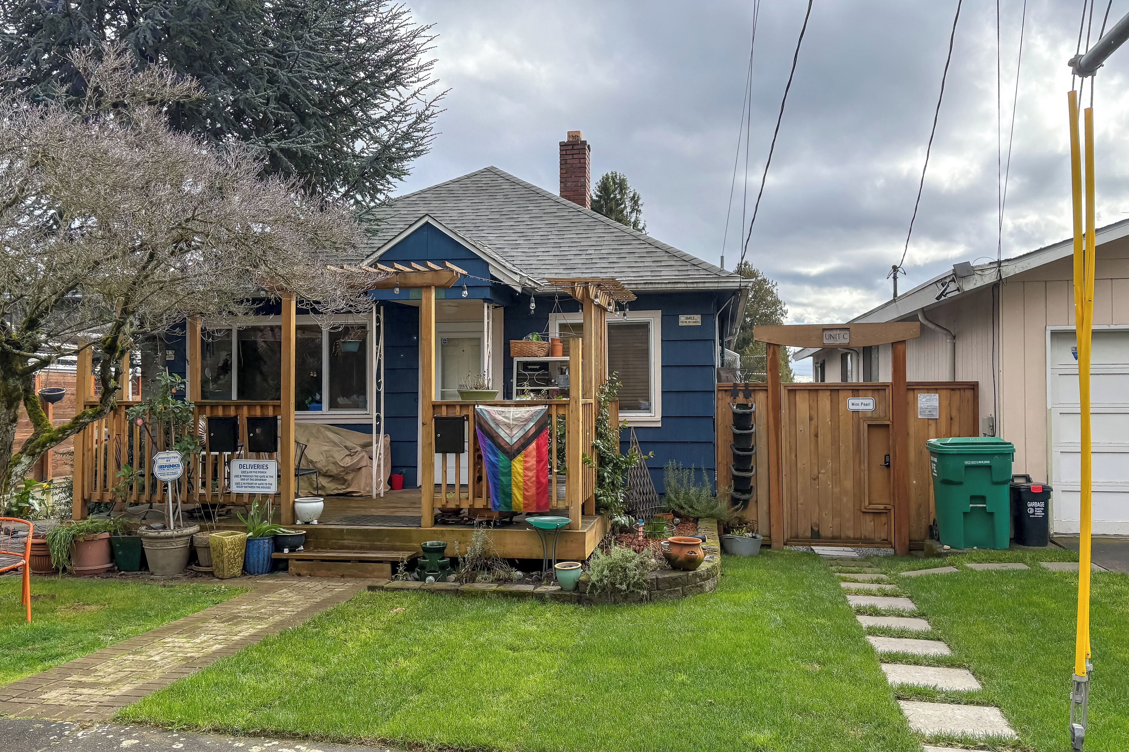 Una casa con porche, un pequeño jardín y valla de madera.