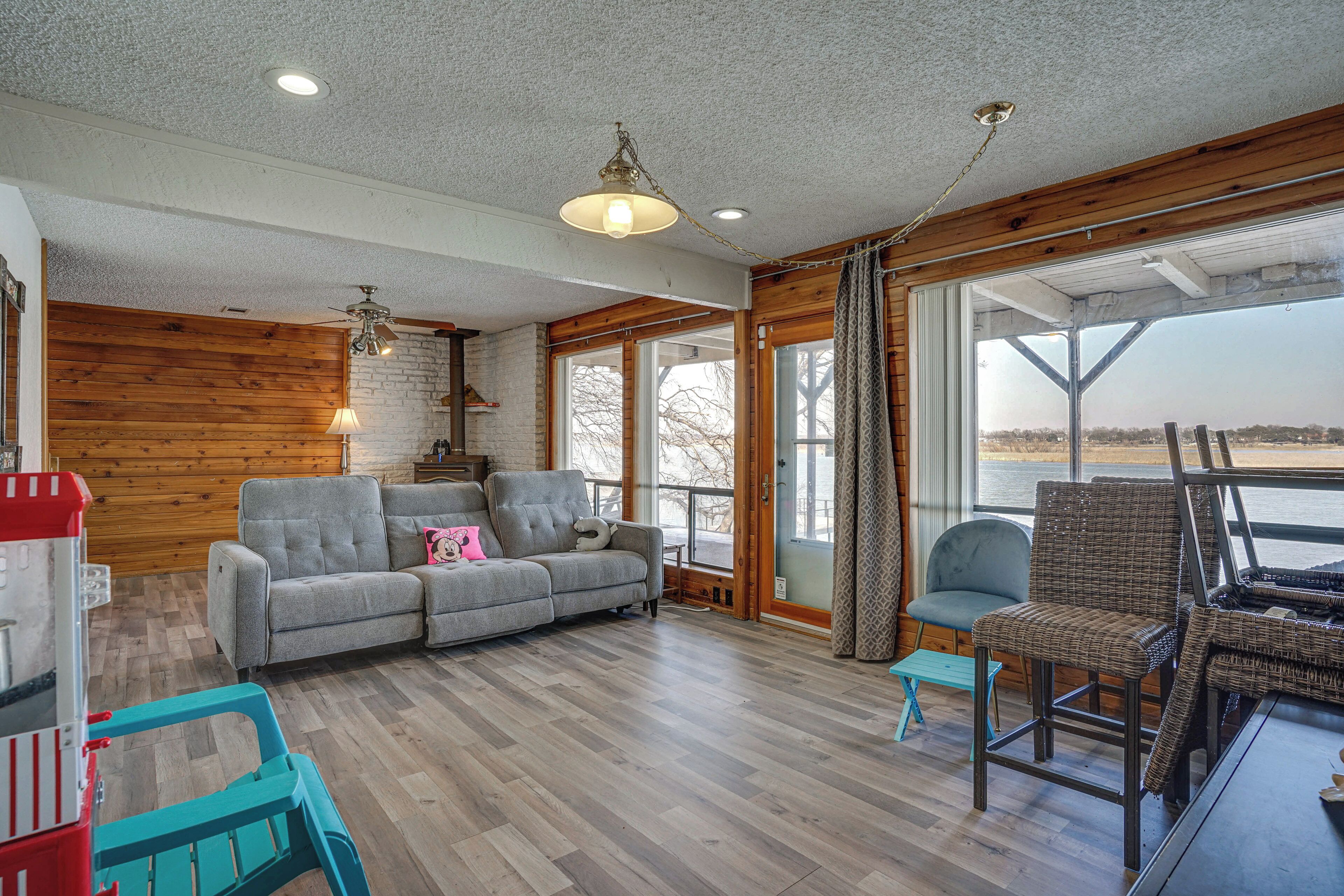 A spacious living room with a grey sofa, a wicker chair, and a small table.