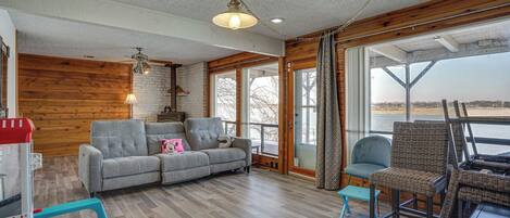 A spacious living room with a grey sofa, a wicker chair, and a small table.