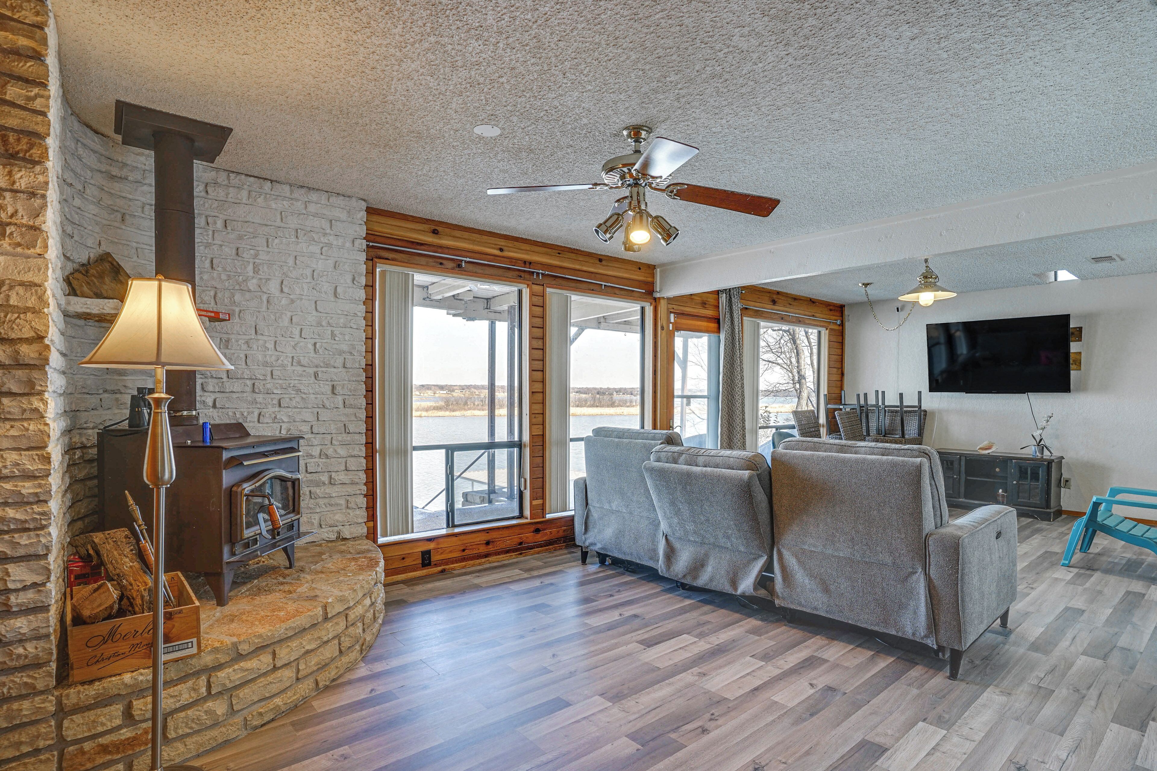 A living room with a fireplace, a ceiling fan, a sofa, and a TV mounted on the wall.