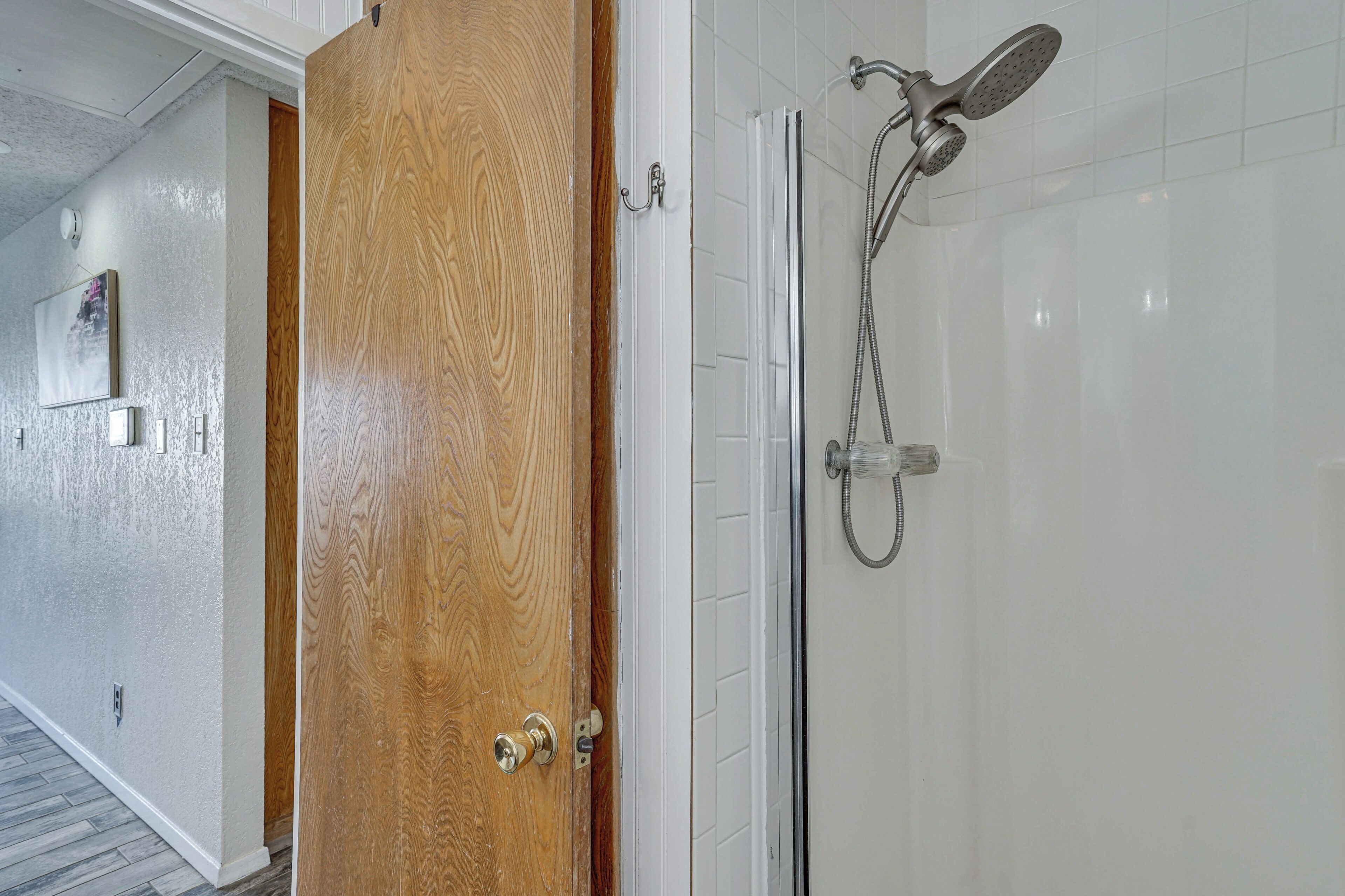 Een houten deur die leidt naar een badkamer met een douchecabine van glas.