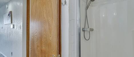Een houten deur die leidt naar een badkamer met een douchecabine van glas.
