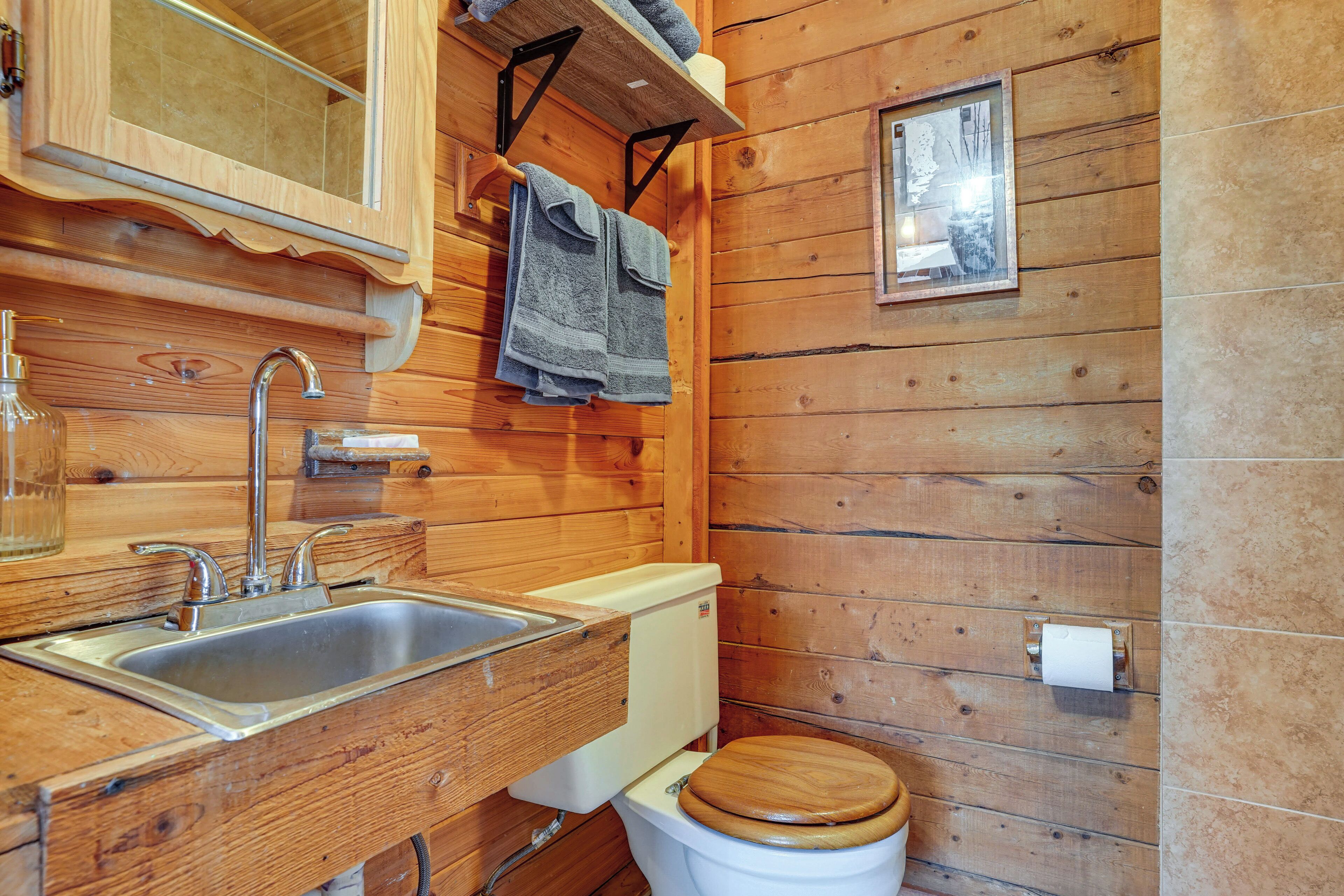 A wooden cabin bathroom with a sink, toilet, and towel rack.