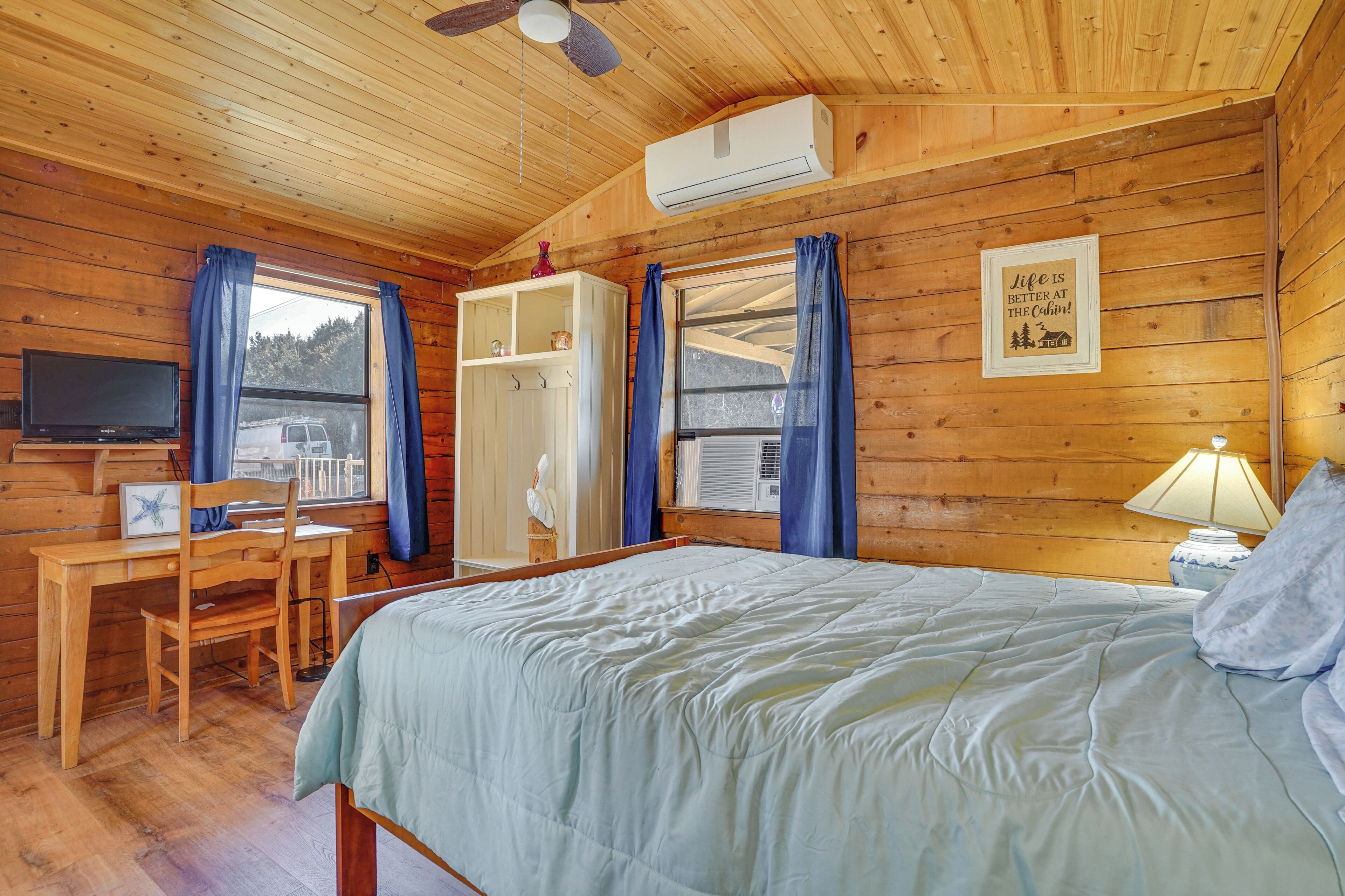 A cabin with a bed, desk, chair, and TV.