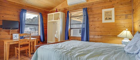 A cabin with a bed, desk, chair, and TV.