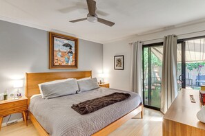 A bedroom with a bed, a ceiling fan, a nightstand, a lamp, a framed picture, and a view of the outdoors. - 2 Mi to Dtwn! Snowbird Gem w/ Pool in Palm Springs (Palm Springs)